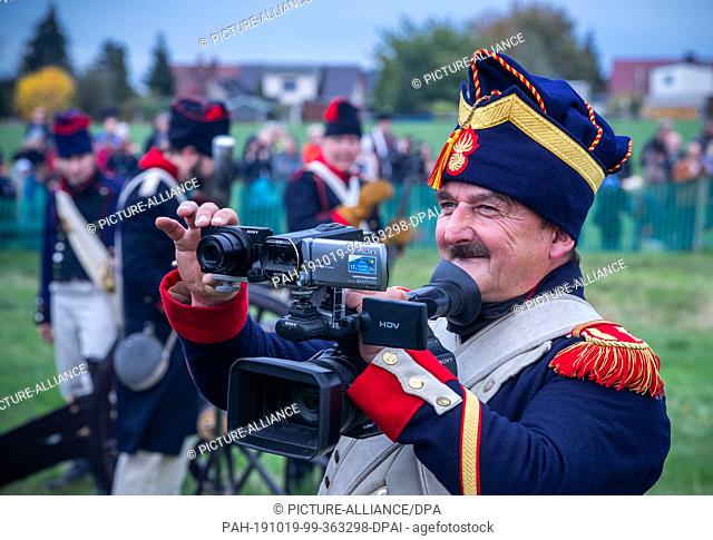 19 October 2019, Saxony, Leipzig: A member of a military-historical association films the scenery of the historical battles of the Battle of the Nations near...