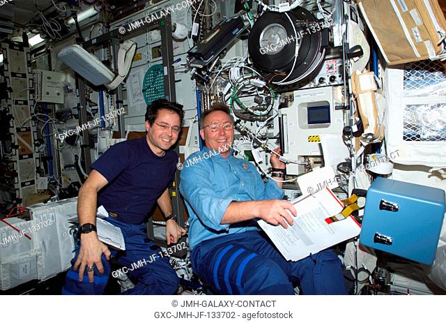 Astronauts Daniel W. Bursch (left), Expedition Four flight engineer, and Jerry L. Ross, STS-110 mission specialist, work in the Destiny laboratory on the...