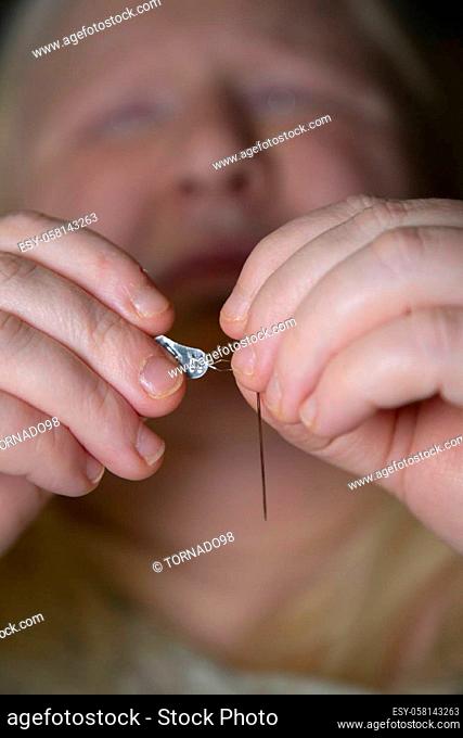 Legally blind woman threading a needle with a threader