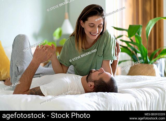 Playful young couple embracing each other on bed at home