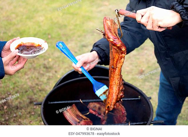 Man brushing sauce on barbecue spare ribs in winter time