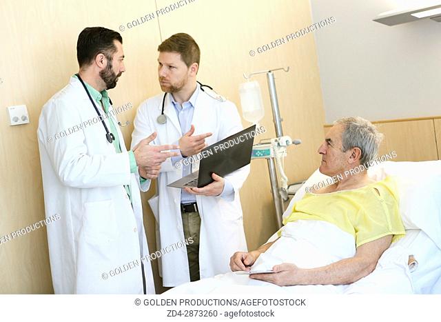 Patient in hospital room attended by doctors