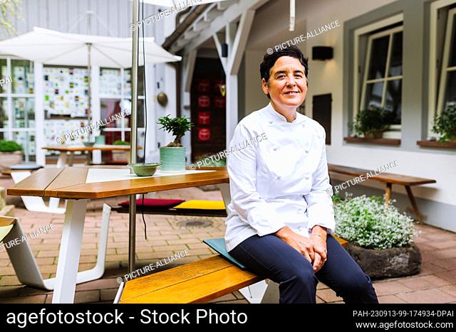 PRODUCTION - 31 August 2023, Baden-Württemberg, Sulzburg: Douce Steiner sits in the courtyard of her two-star Hirschen restaurant