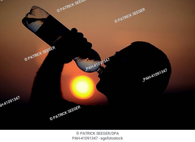 (ILLUSTRATION) An illustration dated 16 July 2013 shows a man drinking from a bottle of mineral water at sunset in Freiburg, Germany, 16 July 2013