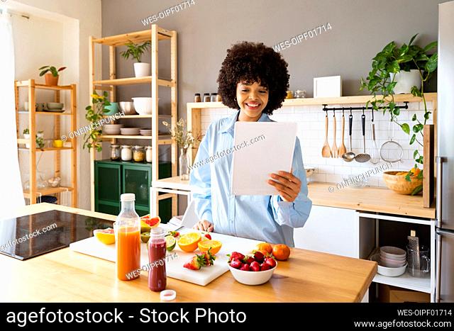 Happy woman using tablet PC standing in kitchen at home