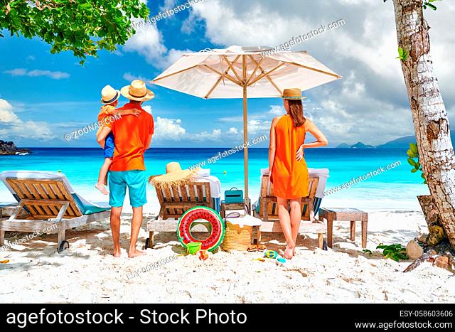 Family on beautiful Petite Anse beach, young couple with three year old toddler boy. Summer vacation at Seychelles, Mahe