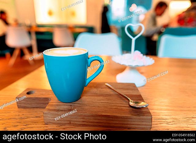 Hot cappuccino coffee in coffee shop on wooden table, close angle