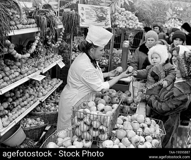 December 1-22, 1981. Murmansk, USSR. A saleswoman shows vegetables and fruits to customers in shop No. 4 of the Murmansk Gorplodoovoshchtorg (city department of...