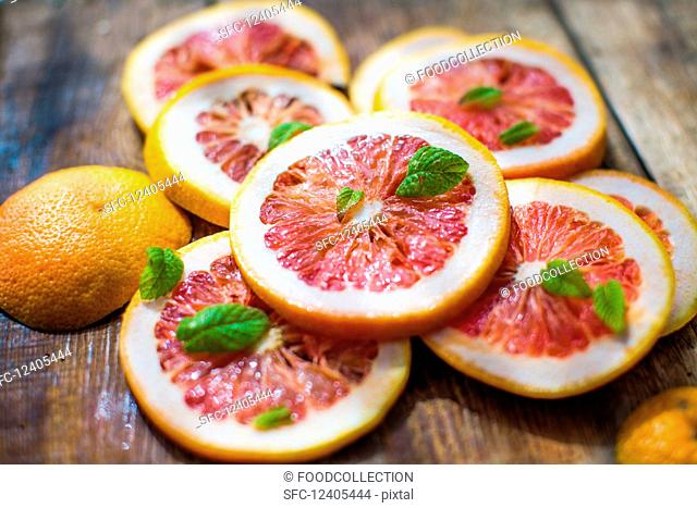 Pink grapefruit slices with mint leaves on a wooden background