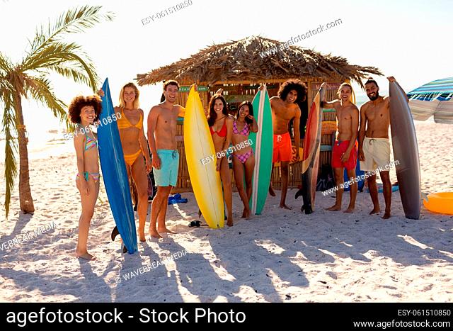Young mixed race people holding surf boards on beach