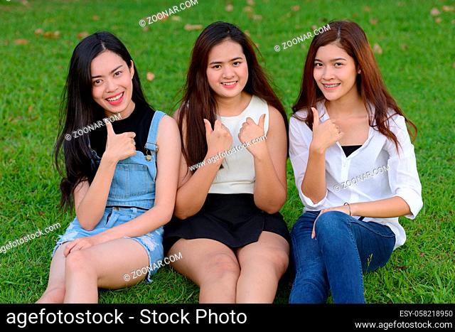 Portrait of three young Asian women as friends together relaxing at the park outdoors