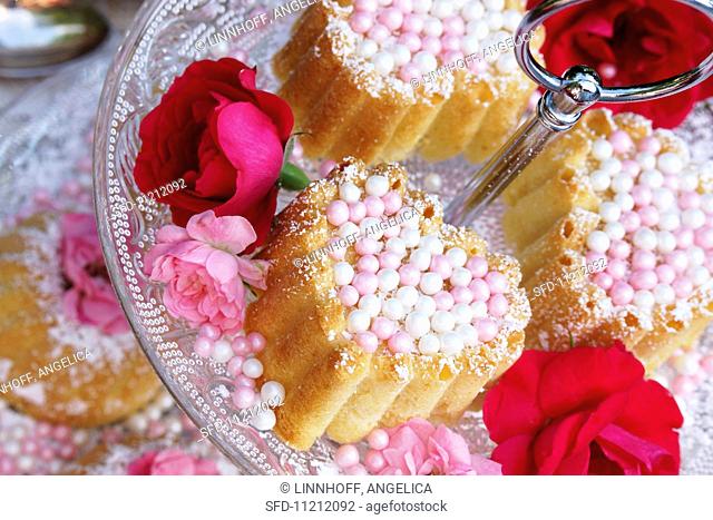 Small Bundt cakes with sugar pearls and flower decoration on a tiered cake stand