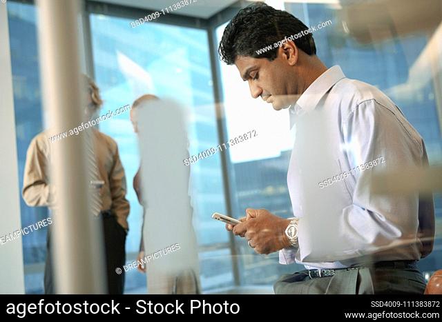Indian businessman text messaging on cell phone