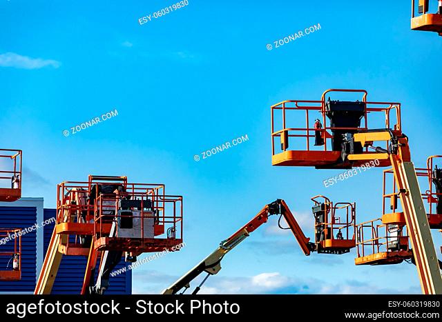A group of raised cherry pickers, aerial work platforms, are seen in an elevated state in storage, hydraulic mobile cranes with copy space