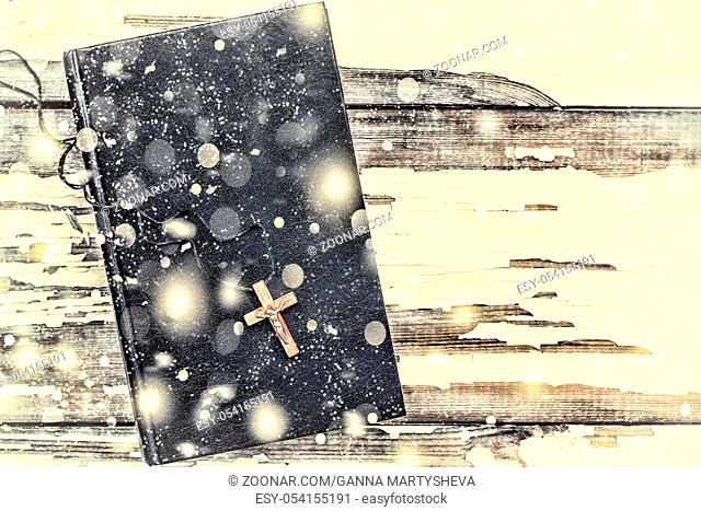 Christmas. Bible and cross on a white background old. Falling snowflakes. close up
