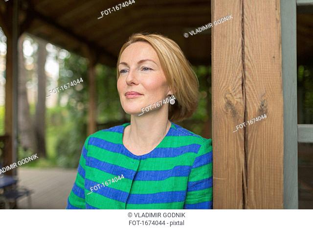 Thoughtful woman leaning on wooden wall in gazebo at park