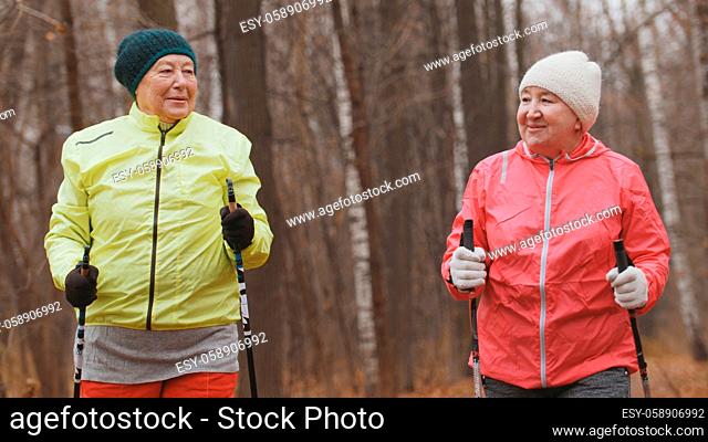 Nordic walking for elderly women outdoor - two happy senior ladies have training outdoor - portrait