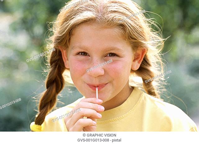 Portrait of a young girl holding a toothpick in her mouth