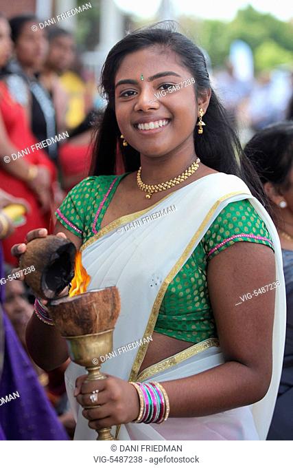 CANADA, SCARBOROUGH, 01.08.2015, A Tamil Hindu girl holds a flaming coconut as she, along with hundreds of devotees, escort the large wooden chariot carrying...