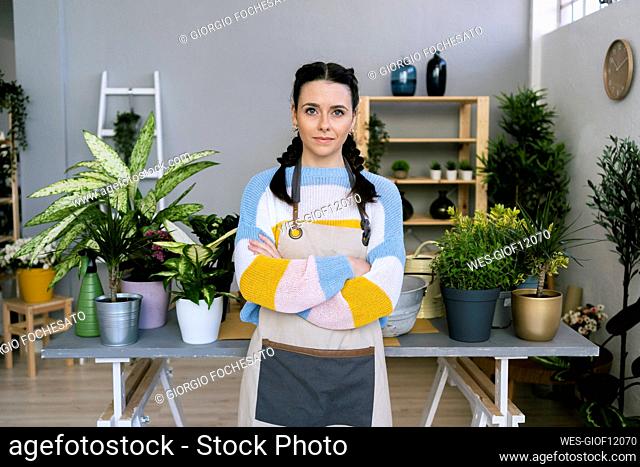 Confident female gardener standing by table in workshop