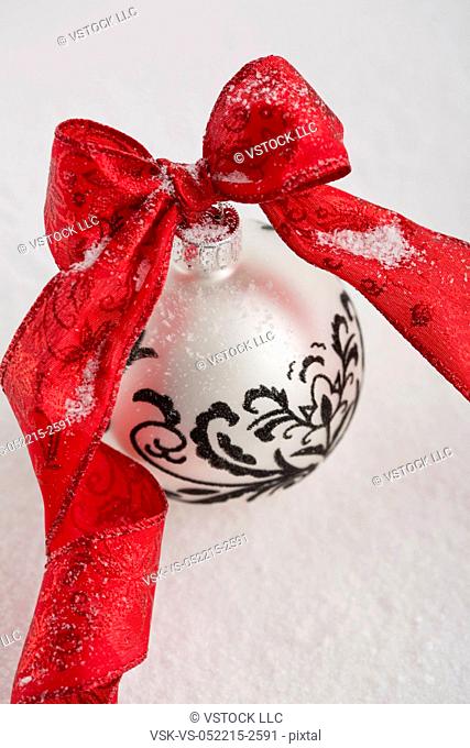Christmas bauble with red ribbon on fake snow