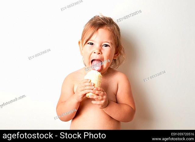 Child eating ice cream in studio shot. Funny happy toddler with summer food. High quality photo
