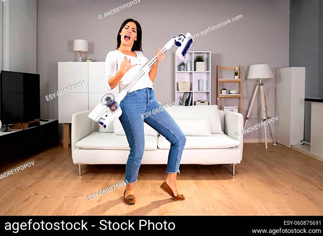 Happy Female Dancing And having Fun With Vacuum Cleaner At Home