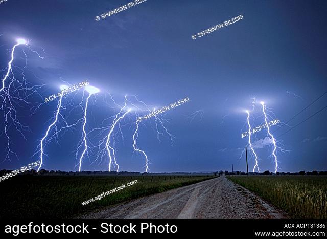 Storm with cloud to ground lightning flashing over old rural road in Kansas United States 4 image composition