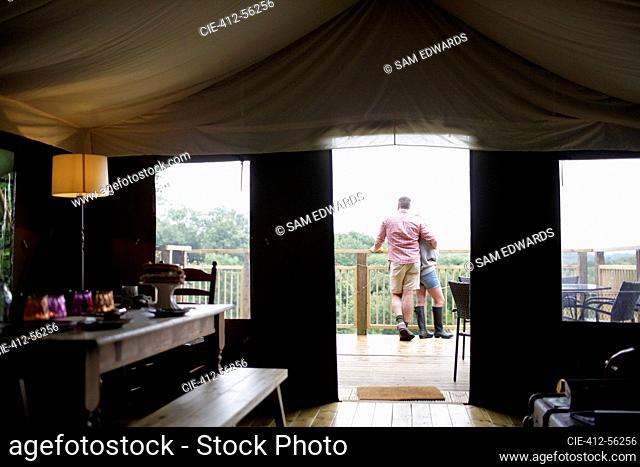 Affectionate couple hugging outside yurt cabin on balcony