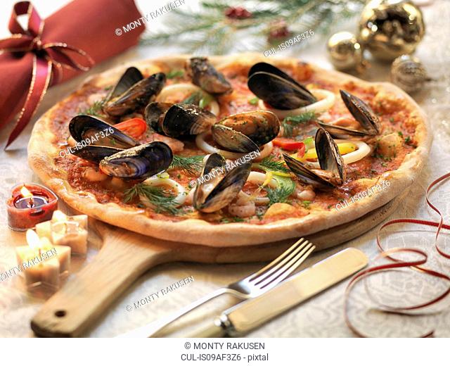 Homemade seafood pizza topped with calamari, prawns and mussels with festive decorations