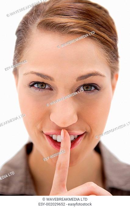 Smiling woman asking for silence against a white background