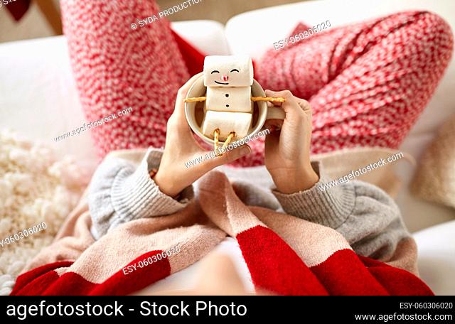 hands with marshmallow snowman in mug on christmas