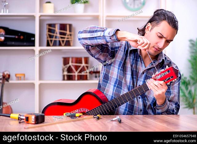 The young handsome repairman repairing guitar