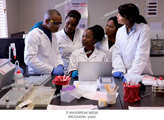 Group of laboratory technicians discussing over laptop