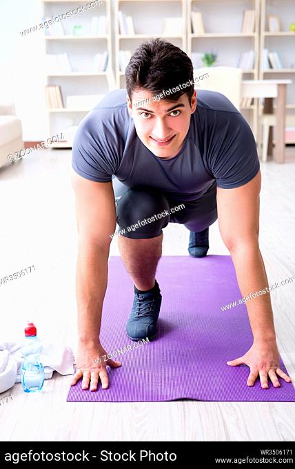 Young man exercising at home in sports and healthy lifestyle concept