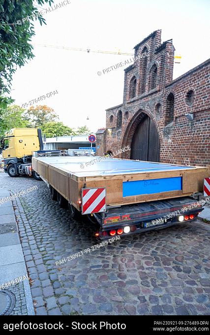 21 September 2023, Mecklenburg-Western Pomerania, Stralsund: A truck maneuvers a pane weighing several tons to the construction site in Stralsund's medieval old...