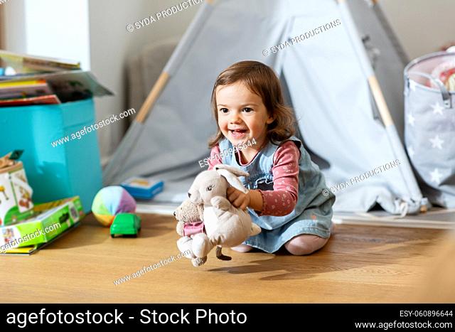 happy baby girl playing with soft toys at home