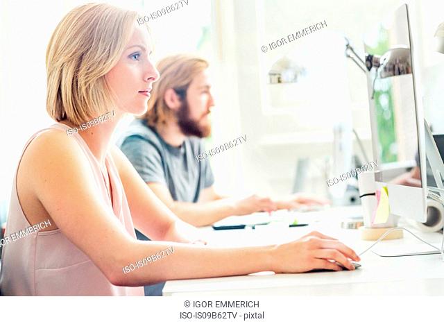 Male and female designers using desktop computers in creative studio