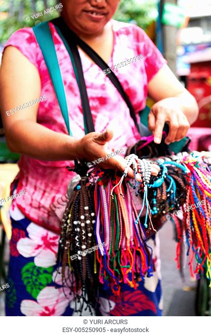 Cropped view of a Thai woman selling bracelets at a market