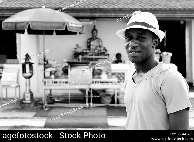 Portrait of young African tourist man as backpacker exploring the city of Bangkok in black and white