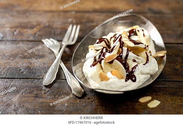 A banana split in a silver bowl on a wooden surface