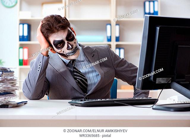 Businessman with scary face mask working in office