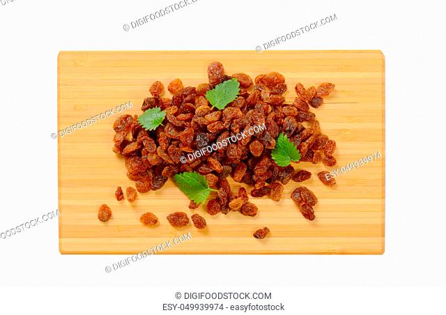 pile of sweet raisins on wooden cutting board