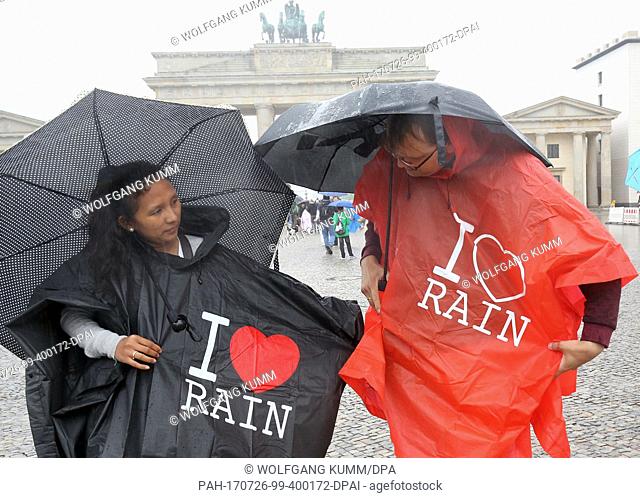 Tourists from the Philippines put on raincapes in addition to their umbrellas in front of the Brandeburg Gate under pouring rain and temperatures of 16 degreees...