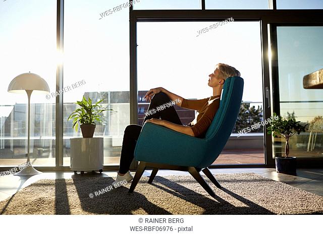 Woman sitting in armchair in sunlight with closed eyes