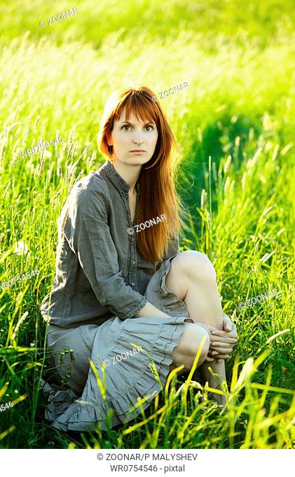sad redhead woman in grass