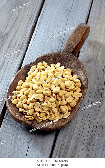 Wooden shovel with peanuts on wooden table