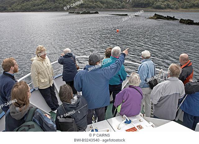 guide on a tourist ship showing shipwrecks which are standing out of the water to the visitors, United Kingdom, Scotland