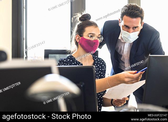 Business people wearing face mask having discussion while working at office