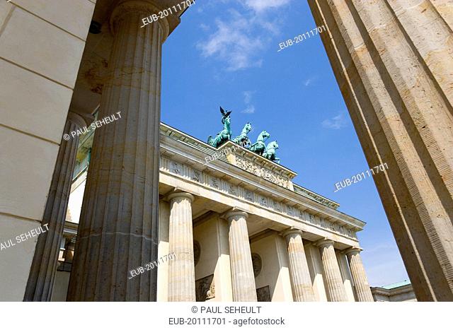 Mitte Brandenburg Gate or Bransenburger Tor seen between columns in Pariser Platz leading to Unter den Linden and the Royal Palaces with the Quadriga of Victory...